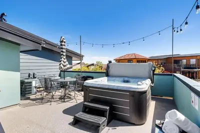a patio with a hot tub and a table on a balcony at Swanky Townhome near Old Town, Breweries & River! in Fort Collins