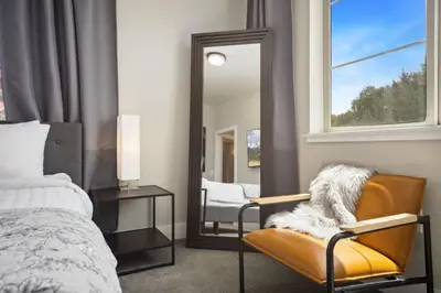 a bedroom with a mirror and a chair and a bed at Swanky Townhome near Old Town, Breweries & River! in Fort Collins