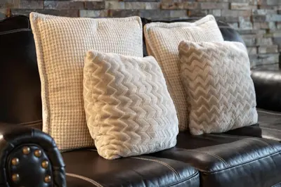 a brown leather couch with three pillows on it at Cozens Pointe I-101 condo in Fraser