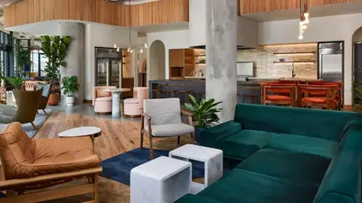 a living room with a green couch and chairs at Catbird Hotel in Denver