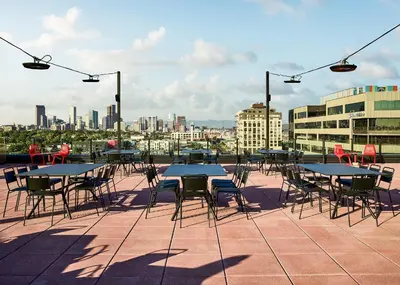 a patio with tables and chairs and a city skyline at Catbird Hotel in Denver