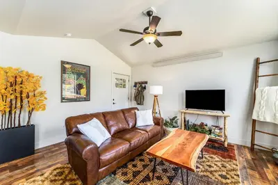 a living room with a brown leather couch and a flat screen tv at Serenity in the Rockies townhouse in Estes Park