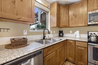 a kitchen with wooden cabinets and a sink at Serenity in the Rockies townhouse in Estes Park