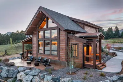 a log cabin with a large window and a patio at Private Lakefront Cabin - Two Large Patios, Jacuzzi, Indoor/Outdoor Fireplace in Estes Park