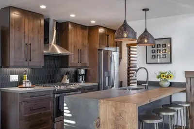 a kitchen with wooden cabinets and a kitchen island with bar stools at Private Lakefront Cabin - Two Large Patios, Jacuzzi, Indoor/Outdoor Fireplace in Estes Park