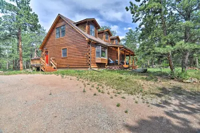 a log cabin in the woods with a dirt road at The Pinecone Palace with Hiking Trail Access! in Lyons