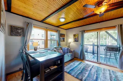 a living room with a table and a balcony at Sunshine & Snowfall in Silverthorne