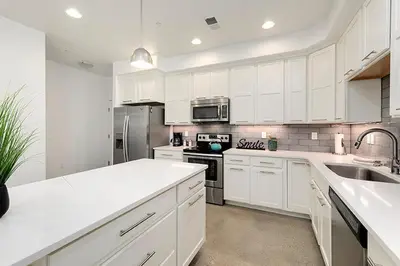 a large white kitchen with white cabinets and appliances at Gorgeous Townhome Steps from the Brewery District! in Fort Collins