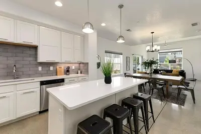 a kitchen with a white counter and a table and chairs at Gorgeous Townhome Steps from the Brewery District! in Fort Collins