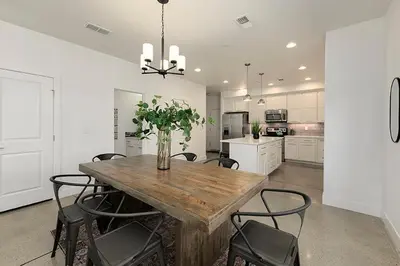a kitchen with a wooden table with chairs and a vase of flowers at Gorgeous Townhome Steps from the Brewery District! in Fort Collins