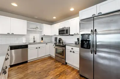 a kitchen with white cabinets and a stainless steel refrigerator at Amazing Urban Townhome near Breweries and River! in Fort Collins