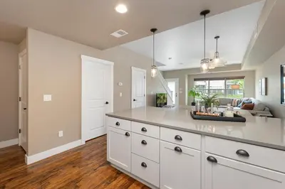 a large kitchen with white cabinets and a living room at Amazing Urban Townhome near Breweries and River! in Fort Collins
