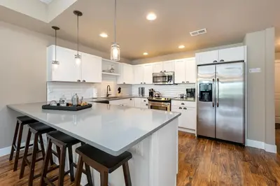 a kitchen with white cabinets and a stainless steel refrigerator at Amazing Urban Townhome near Breweries and River! in Fort Collins