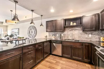 a kitchen with wooden cabinets and a large clock on the wall at Spectacular Home near Breweries & River District! in Fort Collins
