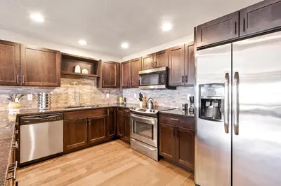 a kitchen with wooden cabinets and stainless steel appliances at Spectacular Home near Breweries & River District! in Fort Collins