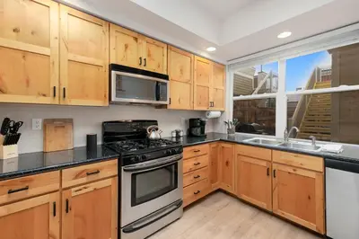 a kitchen with wooden cabinets and a large window at Hip Old Town North Gem! Near Breweries and River! in Fort Collins