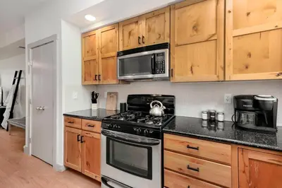 a kitchen with wooden cabinets and a stove and microwave at Hip Old Town North Gem! Near Breweries and River! in Fort Collins