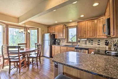 a kitchen with wooden cabinets and a table and chairs at 3-Story Home with Balcony about 6 Mi to Winter Park! in Fraser