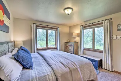 a bedroom with a large bed and two windows at 3-Story Home with Balcony about 6 Mi to Winter Park! in Fraser