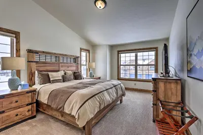 a bedroom with a bed and a desk and windows at Luxe Rocky Mtn Retreat with Hot Tub - By Winter Park in Tabernash