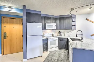a kitchen with white appliances and blue cabinets at Cozy Ski-InandOut Winter Park Studio with Hot Tubs! in Winter Park