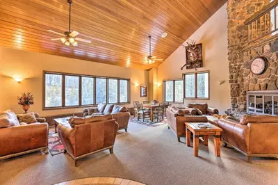 a living room with leather furniture and a stone wall at Cozy Ski-InandOut Winter Park Studio with Hot Tubs! in Winter Park