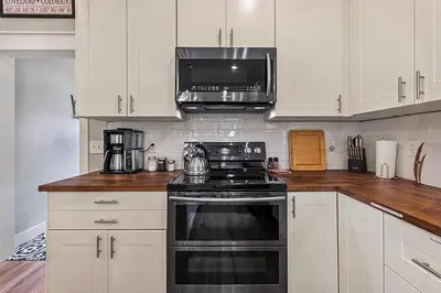 a kitchen with white cabinets and a black stove top oven at Cozy Chic Home In Downtown Loveland! in Loveland