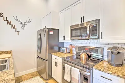 a kitchen with white cabinets and a stainless steel refrigerator at 5 Mi to Ski Resort Breck Penthouse Studio in Breckenridge