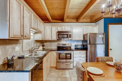 a kitchen with wooden cabinets and a stainless steel refrigerator at F201 Treehouse condo in Silverthorne