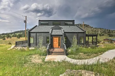 a black house on top of a grassy hill at Modern Evergreen Duplex Off I-70 with Mountain Views in Idaho Springs