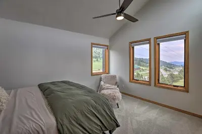 a bedroom with a bed and a fan and windows at Modern Evergreen Duplex Off I-70 with Mountain Views in Idaho Springs