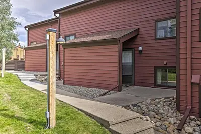 a red house with a garage next to a driveway at Warm Fraser Townhome with Community Amenities! in Fraser