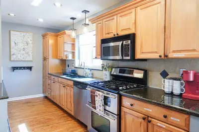 a kitchen with wooden cabinets and a stove top oven at Family-Friendly Retreat 30-Night Minimal in Denver