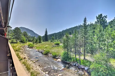 a train traveling down a river next to a forest at Estes Park Condo about 1 Mi to RMNP! in Estes Park