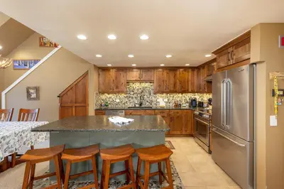a kitchen with wooden cabinets and a large island with bar stools at 2105 The Pines condo in Keystone