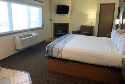 a hotel room with a bed and a fireplace at AmericInn by Wyndham Windsor Ft. Collins in Fort Collins