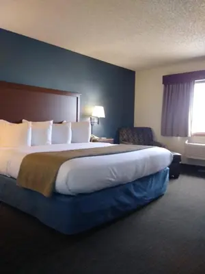 a hotel room with a large bed and a chair at AmericInn by Wyndham Windsor Ft. Collins in Fort Collins