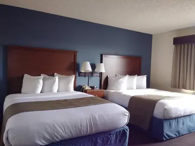 a hotel room with two beds with white pillows at AmericInn by Wyndham Windsor Ft. Collins in Fort Collins