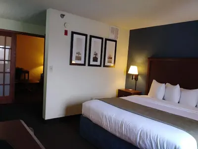 a hotel room with a large bed with white sheets at AmericInn by Wyndham Windsor Ft. Collins in Fort Collins
