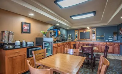 a kitchen with a wooden table and a table and chairs at AmericInn by Wyndham Windsor Ft. Collins in Fort Collins
