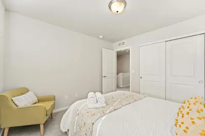 a white bedroom with a bed and a chair at Centrally Located, Comfortable Home in Music City in Fort Collins