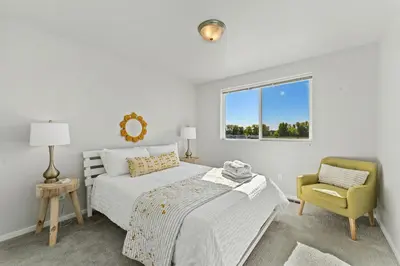 a bedroom with two beds and a chair and a window at Centrally Located, Comfortable Home in Music City in Fort Collins