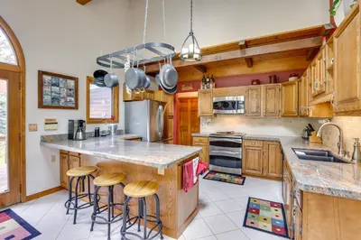 a kitchen with wooden cabinets and a island with bar stools at Silver Plume Mountain Haven with Views and Deck! in Silver Plume