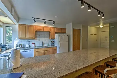 a kitchen with wooden cabinets and a large counter top at Less Than 2 Mi to Frisco Adventure Park Cozy Townhome! in Frisco