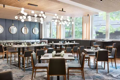 a dining room with tables and chairs and windows at The Slate Hotel Denver Downtown, Tapestry by Hilton in Denver