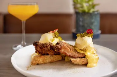 a white plate with a sandwich and a glass of orange juice at The Slate Hotel Denver Downtown, Tapestry by Hilton in Denver