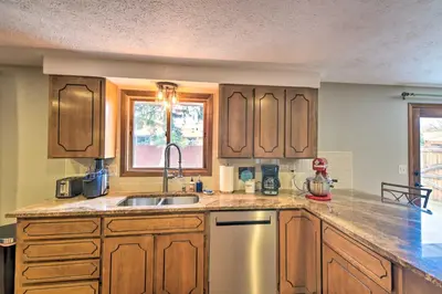 a kitchen with wooden cabinets and a sink at Loveland Getaway with Fire Pit and Ping Pong Table! in Loveland