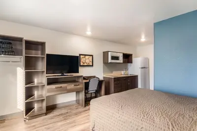 a hotel room with a bed and a desk with a computer at WoodSpring Suites Thornton-North Denver in Thornton