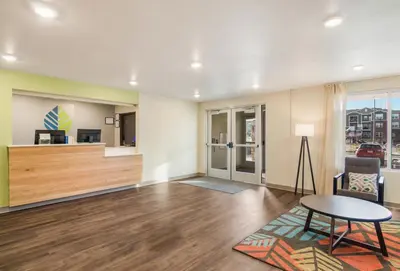 an empty living room with a table and a couch at WoodSpring Suites Thornton-North Denver in Thornton