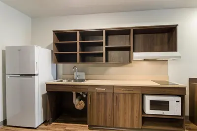 a kitchen with a white refrigerator and a sink at WoodSpring Suites Thornton-North Denver in Thornton
